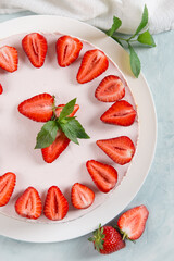 Sweet breakfast, delicious cheesecake with fresh strawberries and mint, homemade recipe without baking, on a blue stone table. Copy space.