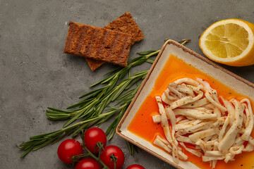 squid in a sauce on a plate with bread, lemon and razmorin