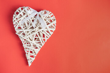 Wicker heart ornament on a red colored background.