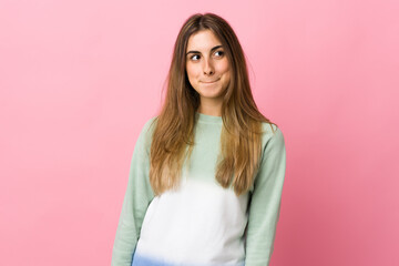 Young woman over isolated pink background having doubts while looking up