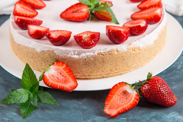 Sweet breakfast, delicious cheesecake with fresh strawberries and mint, homemade recipe without baking, on a dark blue stone table. Copy space.