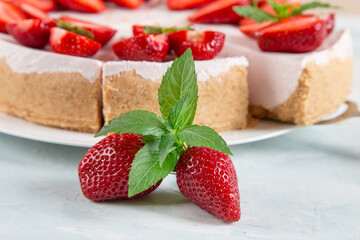 Sweet breakfast, delicious cheesecake with fresh strawberries and mint, homemade recipe without baking, on a blue stone table. Copy space.