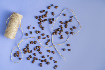 Jute twine and fresh coffee beans on the purple table background, 