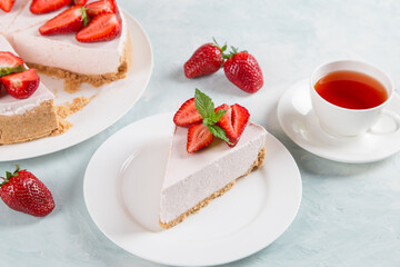 Sweet breakfast, tea and delicious cheesecake with fresh strawberries and mint, homemade recipe without baking, on a blue stone table. Copy space.