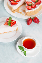 Sweet breakfast, tea and delicious cheesecake with fresh strawberries and mint, homemade recipe without baking, on a blue stone table. Copy space.