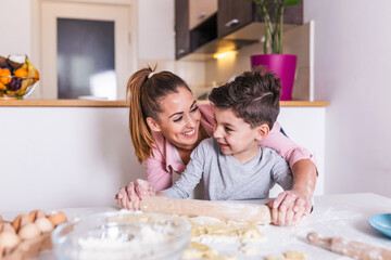 Obraz na płótnie Canvas Happy loving family are preparing bakery together. Mother and child son boy are cooking cookies and having fun in the kitchen. Homemade food and little helper.