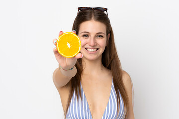 Young caucasian woman isolated on white background in swimsuit and holding an orange