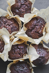Macro picture of chocolate muffins covered in brow paper on black background. Cope space concept. Food wallpaper for blog with home made small baked cake. Sweet, tasty snack for breakfast.