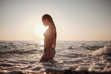 Fototapeta na wymiar Beautiful Model Girl making splash in the sea at sunset
