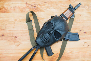 assault rifle AK-47 on a wooden surface and face mask
