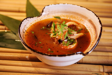 Bouillabaisse soup or Tom Yam on the bamboo background. Close up view. Apetizing soup with seafood. 