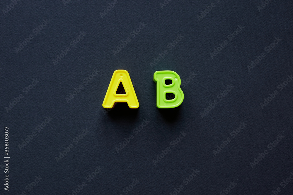 Fototapete yellow and green letters a and b uppercase. capital letters a and b isolated on black background; co