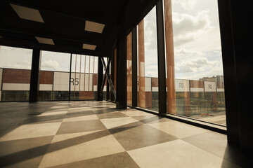 Background image of empty office building interior with floor to ceiling windows lit by sunlight,...