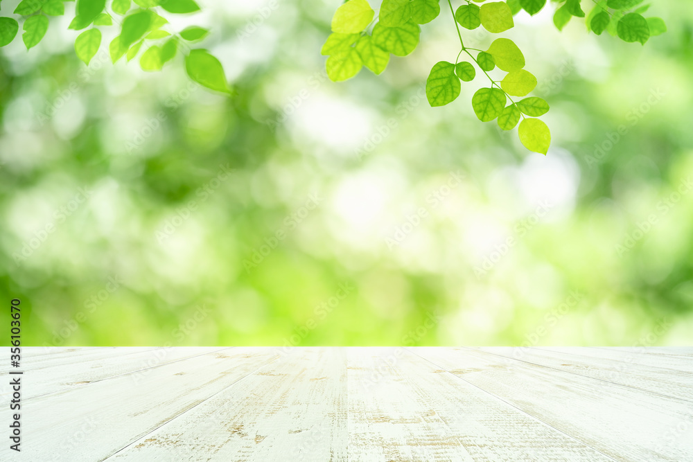 Wall mural fresh green leaves nature with bokeh on empty wooden table background for product display template a
