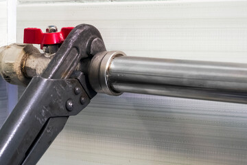 Close up of hand repairing pipes with wrench. Plumber fixing pipe with adjustable wrench.