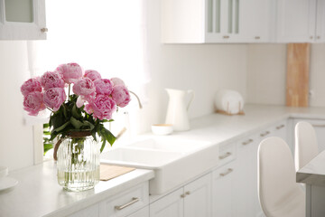 Vase with bouquet of beautiful pink peonies in kitchen. Space for text © New Africa
