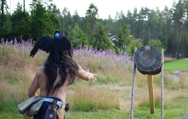Indian throwing an ax at a target. Rear view