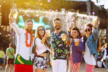 Group of friends with beer dancing and having fun at music festival together. Summer Beach party,...
