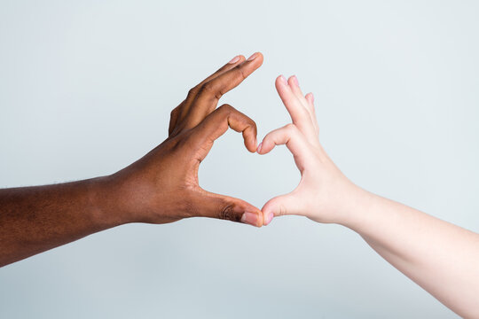 Closeup photo of two arms different race skin color multiracial couple best friends antiracism issue concept help together showing heart figure love save world isolated grey background