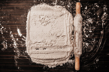 Flour on a wooden table. Rolling pin on the table. View from above. Close-up photo