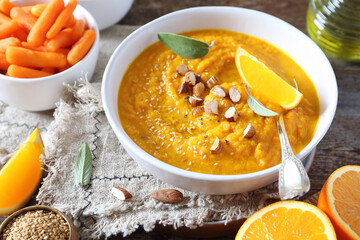Vegetarian carrot soup with orange juice, sesame and almond nuts dressing, rustic style