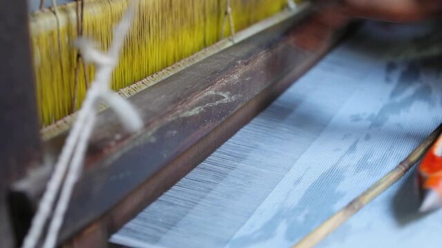 Male hand weaving cloth in big machinery in cloth manufacturing cottage textile industry