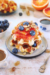 Traditional Belgian waffles, blood oranges and blueberries dressing and coffee for sweet breakfast