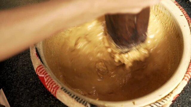 Hand closeup mixing peanut and water to make groundnut soup in bowl