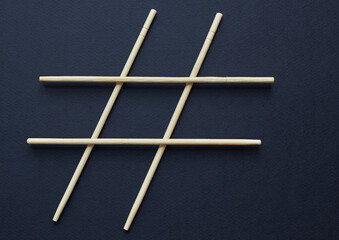 Hashtag sign made of wooden sticks isolated on black background; social media and creativity concept
