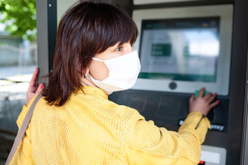 Rear view of an unidentified woman in a protective mask points her finger at blurry information...