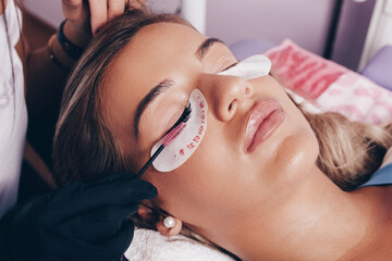 Beautiful young woman getting eyelash extension procedure. Cosmetics and body care concept.