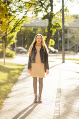 Happy young woman looks at camera and sends a kiss on rainy and sunny day