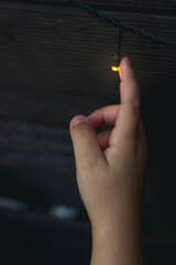 Finger zeigt auf eine Glühbirne einer Lichterkette