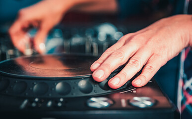 DJ Hands creating and regulating music on dj console mixer in concert nightclub stage.