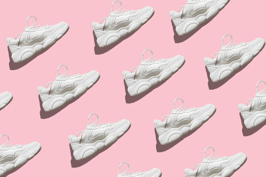 Regular seamless pattern of light sneakers with a hard shadow on a pink background. Photo collage. Fashion blog, sport lifestyle. Printing on fabric, wrapping paper.