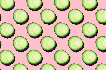 Regular seamless creative pattern of cucumber slices on a pink background.Photo collage,hard lightshadow,pop art design. Food blog, vegetable background. Printing on fabric, wrapping paper.Top view.
