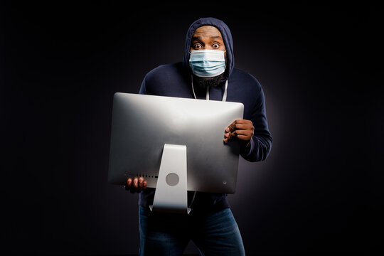 Photo of astonished afro american guy rob computer screen theft from digital technology shop wear sweater jeans medical mask isolated over black color background