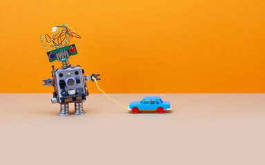 Robot plays with a vintage toy car. Orange background, copy space