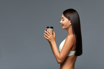 Beautiful Italian woman with coffee in lingerie, on gray background with copy space. Advertising banner, good and vigorous morning. Concept girl and coffee - great mood in the morning.