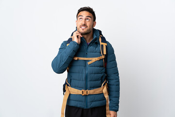 Fototapeta premium Young mountaineer man with a big backpack isolated on white background thinking an idea