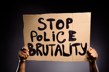 Close up photo of afro american hand hold cardboard banner show stop police brutality message isolated over black color background - obrazy, fototapety, plakaty