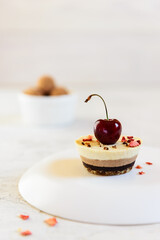 Cashew cake with chocolate and lemon, decorated with cherries and freeze dried berries on a light table. No sugar, gluten, lactose.
