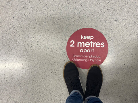 A social distancing sticker on the floor warning people to stay 2 metres apart