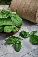 Fresh spinach in an old bowl on a gray background. Selective focus, horizontal. environmental...