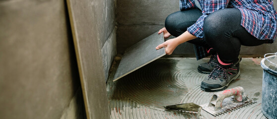 Unrecognizable female builder laying a new tile floor on a terrace