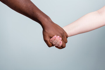 Closeup photo of two hands arms different race multinational couple best friends anti racism issue help together holding together love save world isolated grey color background
