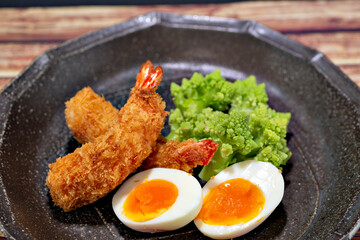 Dinner plate of fried shrimps, boiled cauliflower romanesco and boiled egg.