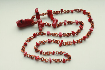 Red beads made of natural coral and copper wire on a white background.