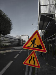 A men at work and a narrow road sign on the streets of Nantes on a monochrome backdrop 