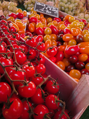 Ripe red and yellow cherry tomatoes for sale on wooden racks at a market in Nantes france